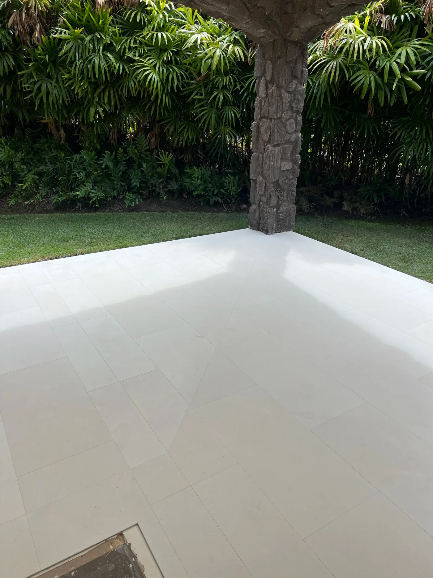 Large-format limestone lanai beside a lava-rock column in Maui